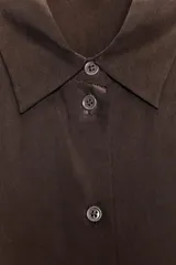 Camisa marrón de seda 100% con cuello solapa, manga larga con puños abotonados, bajo asimétrico redondeado y cierre frontal con botones.