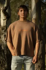 Remera marrón de manga corta confeccionada en punto Prato, con bordado frontal con la palabra 'bouuwana'. De calce relajado y textura suave.