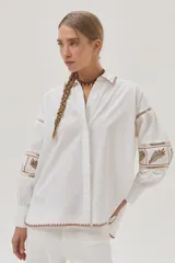 Camisa blanca de mangas largas abullonadas con bordados combinados y guardas, además de delicados bordados en el cuello y el bajo.