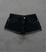 Short de jean negro con tachas plateadas en los laterales y ruedo desflecado.