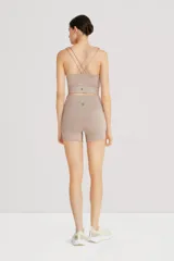 Top deportivo color beige, de cintura ancha, realizado en tela doble suave y de alta elasticidad. Detalle de breteles cruzados en la espalda.