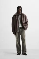 Sobrecamisa marrón de efecto piel con interior de borreguillo combinado a tono, de corte relaxed fit, cuello solapa, manga larga con puños abotonados, bolsillos de plastrón en pecho y laterales en cadera, efecto lavado y cierre frontal con botones a presión.