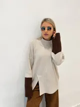 Sweater de punto color avena, con cuello alto y mangas largas con puños marrones.