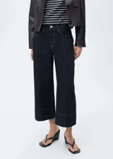 Pantalón de jean azul oscuro, corte cropped wide leg, tiro medio, con bolsillos delanteros y traseros, cierre frontal con cremallera y botón, y costuras a la vista.