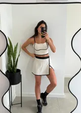 Conjunto deportivo color beige con ribetes negros, compuesto por un top con tirantes finos y una minifalda con short interno.