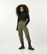Pantalón jogger color verde militar, con cintura elástica ajustable con cinturón de hebilla plástica. Tiene bolsillos laterales tipo cargo con fuelle y puños elásticos.
