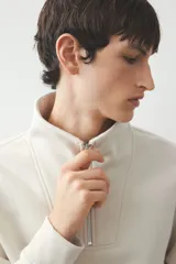 Buzo color crema de tejido pesado con interior cepillado, cuello elevado, medio cierre y hombros caídos. Puños y bajo en punto acanalado. Corte estándar.