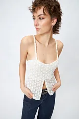 Top blanco de encaje con breteles finos, corte en la cintura y abertura frontal.