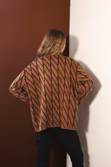 Cárdigan tejido con diseño de rombos rojos y negros, con mangas largas y cierre frontal con botones.