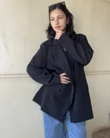 Blazer negro de corte oversize, con solapas de muesca, cierre cruzado con doble botonadura y bolsillos delanteros con solapa.