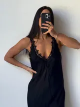 Vestido largo negro con breteles finos, escote en V y detalles de encaje en el escote y en el ruedo.