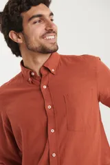 Camisa azul marino de lino y algodón, con cuello abotonado, manga larga con puños enrollados, bolsillo de parche en el pecho y cierre frontal con botones.