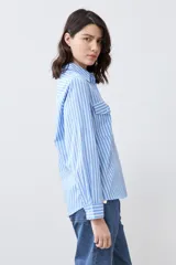 Camisa celeste con rayas verticales blancas, de manga larga y corte clásico, con cuello camisero y dos bolsillos con solapa en el pecho.