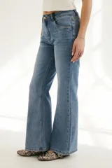 Pantalón de jean azul de corte acampanado, con bolsillos delanteros y traseros, y detalle de cuero sintético en la cintura.