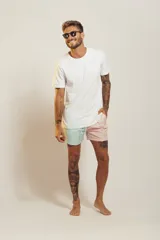 Short de baño para hombre, tiro medio, con estampado tropical en tonos rosados, verdes y blancos. Posee cintura elástica con cordón de ajuste trenzado y bolsillos laterales.