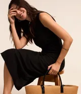 Vestido midi negro sin mangas, con cuello redondo y detalle drapeado lateral.
