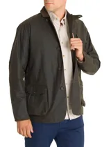 Chaqueta verde de tela canvas con tratamiento de cera Wax, cuello de cotelé, cierre con botones, tres bolsillos frontales y dos interiores.