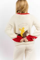 Sweater tejido a mano en lana merino color crudo, con cuello y puños en rojo. Presenta un diseño con motivos de un cowboy y estrellas.