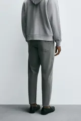 Jeans de denim de algodón, color negro lavado, con tiro medio, corte ajustado en cadera y muslos, y pierna que se estrecha hacia el tobillo. Presenta cinco bolsillos y cierre frontal con cremallera y botón.