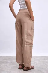 Pantalón cargo color beige con bolsillos laterales y bordados en hilo blanco en contorno de bolsillos y ruedo.