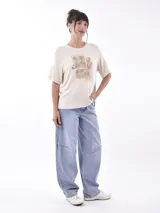 Remera blanca de manga corta con cuello redondo y estampado frontal que dice "SAVAGE" con una figura de animal (posiblemente un leopardo o jaguar) hecho de lentejuelas o material brillante. Debajo del estampado principal se lee "LIFE GOES ON ENJOY".