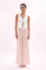 Chaleco tejido de punto color blanco, sin mangas, con escote en V y cierre frontal de botones dorados.