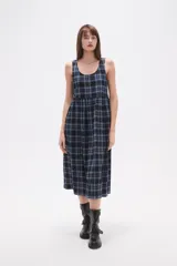 Vestido midi sin mangas confeccionado en algodón con estampado de cuadros en tonos azul y negro. Presenta un diseño holgado con cuello redondo y cierre posterior.