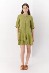 Vestido corto color verde oliva, de lino, con cuello mao, mangas cortas y corte escalonado. Cierre frontal con botones.