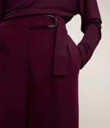 Pantalón wide color borgoña de crepé con cintura alta y hebilla metálica.