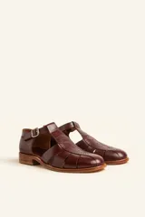 Sandalias de cuero color marrón claro, con diseño de tiras entrecruzadas y hebilla lateral.