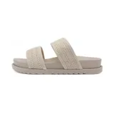 Sandalia plana de mujer con dos tiras anchas sobre el empeine. Las tiras tienen un acabado texturizado que simula tejido o rafia en color beige claro. La plantilla y la suela son del mismo tono neutro y la suela es gruesa con relieve en el borde.