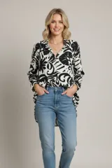 Blusa de manga larga con cuello camisero y estampado abstracto en blanco y negro.