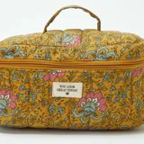 Neceser de tela acolchada color ocre con estampado de flores en tonos rosa y celeste, cierre con cremallera y asa superior.