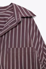 Camisa de manga larga a rayas color borgoña y blanco, con cuello solapa, bolsillo de plastrón en el delantero y cierre frontal con botones.