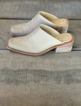 Zuecos color beige con diseño bordado en el empeine, taco de madera y punta cuadrada.
