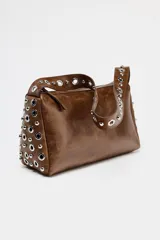 Bolso de hombro color marrón con apliques metálicos plateados en los bordes y en la correa. Cierre con cremallera.