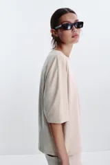 Camiseta color beige de corte amplio, cuello redondo y mangas cortas.