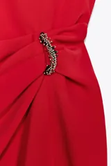 Vestido midi rojo de cuello redondo y sin mangas, con detalle de pliegues y fornitura en la cintura, y abertura frontal en el bajo.