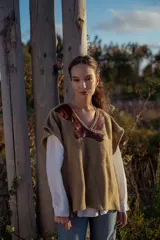 Chaleco tejido color tostado con apliques de cuero marrón en el cuello y detalle de pespunte en el contorno.