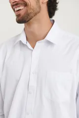 Camisa blanca de corte clásico con botones y un bolsillo en el pecho.