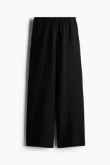 Pantalón negro de lino con cintura elástica, bolsillos laterales y traseros. Piernas rectas con pliegue cosido adelante.