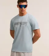 Remera deportiva celeste de poliéster con tecnología Dry, cuello redondo y mangas cortas. Estampa geométrica horizontal en el pecho y recortes en las mangas.