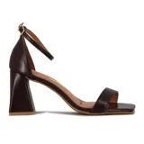 Sandalia de tacón alto color blanco, con una tira delgada sobre los dedos y pulsera con hebilla al tobillo.