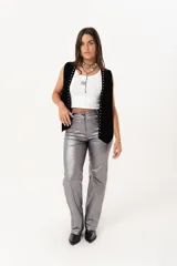 Pantalón plateado de tiro alto confeccionado en gabardina stretch metalizada, con bolsillos y cierre frontal con cremallera y botón.