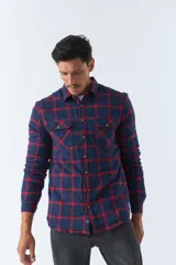 Sobrecamisa de algodón para hombre con interior de corderito, estampado a cuadros en tonos negro, blanco y azul. Tiene cierre de botones, bolsillos tipo cartera y logo en goma. El modelo usa talle M.