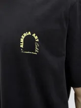 Remera negra de algodón con cuello redondo y manga corta. Estampado en la espalda con la frase "Almeria Art Exhb." y una imagen de un paisaje.