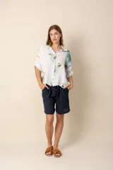 Camisa de lino blanca con estampado de flores azules y verdes, de corte holgado y manga corta.