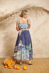 Vestido midi azul con estampado de palmeras y otros motivos tropicales, escote redondo y cinto de rafia.