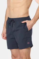 Short de baño azul vibrante, de corte clásico y largo medio, con cintura elástica y cordón ajustable. Cuenta con bolsillos laterales y suspensor de malla fina interior.