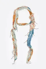 Pañuelo rectangular con estampado tipo patchwork en tonos celeste, naranja y blanco, con flecos de cuentas metálicas.